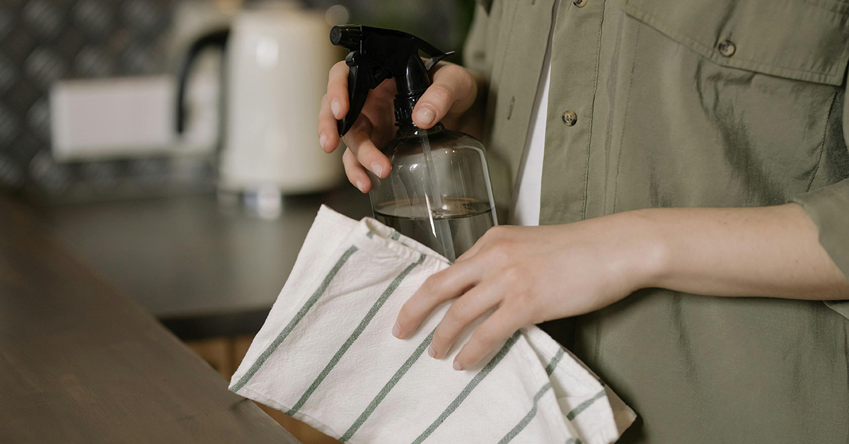 Spray bottle and cleaning cloth in hands